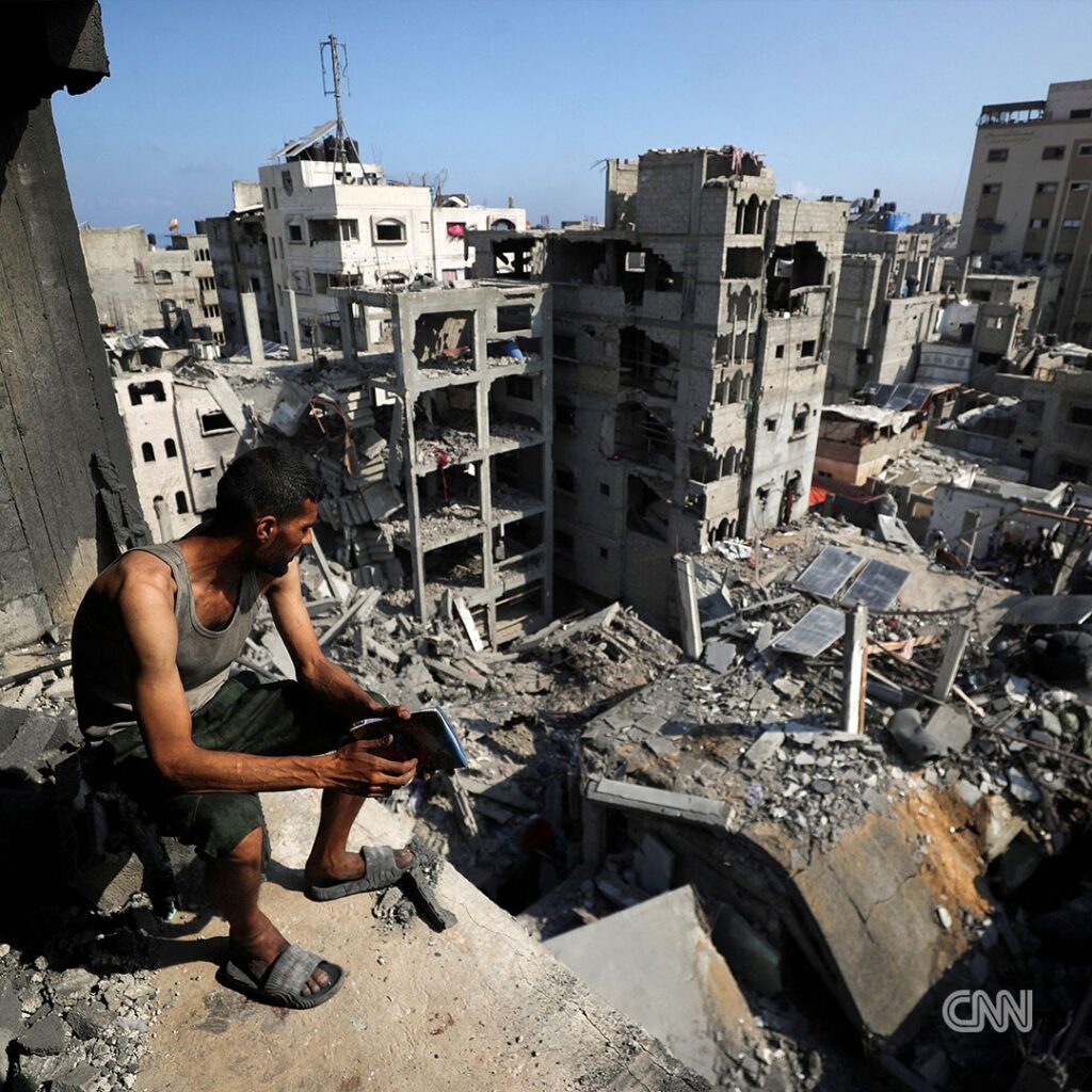 A Palestinian man sits on the ruins of a destroyed building in Gaza City after Israeli airstrikes reduced residential blocks to rubble.